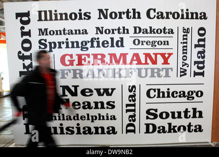 Berlin, Deutschland. 4. März 2014. Ein Arbeiter geht vorbei an einem Poster mit den Namen der US amerikanischen Städten, die von Frankfurt Main geschrieben am Stand von den USA in den Messehallen unter dem Radio Tower Berlin (Funkturm Berlin) in Berlin, Deutschland, 4. März 2014 erreicht werden können. Die International Travel Trade Show (Internationale Tourismusboerse, ITB) öffnet für Besucher am 5. März 2014. Foto: Wolfgang Kumm/Dpa/Alamy Live News Stockfoto