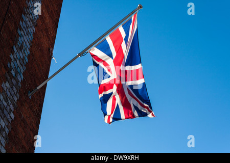 Nationalflagge des Vereinigten Königreichs fliegen von einem Fahnenmast an der Seite eines Gebäudes. Stockfoto