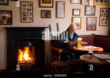 Ein Mann genießt einen Pint am Kamin im Haus-Eckkneipe in Ardara, County Donegal, Irland Stockfoto