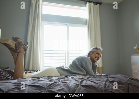 Entspannen Sie sich auf Luxus Bett Reife Frau Stockfoto