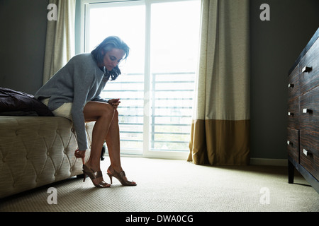 Reife Frau sitzt auf Bett setzen auf high heels Stockfoto