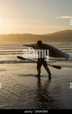 Mann trägt Kajak am Strand zu einem Bahobohosh Zeitpunkt, Makah Bay, Washington, USA Stockfoto