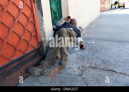 Ein betrunkener Obdachloser Mann stürzte schlafend auf dem Bürgersteig oder Gehsteig in Juayua am Nachmittag. Öffentliche Trunkenheit ist nicht ungewöhnlich Stockfoto