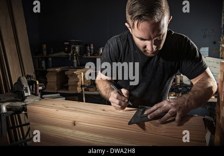 Männliche Tischler messen Holzbrett mit Geodreieck in Werkstatt Stockfoto