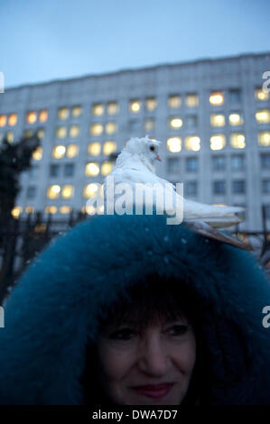 Moskau, Russland. 4. März 2014. Taube, sitzen als Symbol des Friedens, auf ein Habit Frau. Auf dem Hintergrund des Verteidigungsministeriums der Russischen Föderation. Protest gegen den Krieg in der Ukraine. © Anna Sergeeva/ZUMAPRESS.com/Alamy Live-Nachrichten Stockfoto