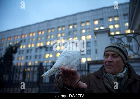 Moskau, Russland. 4. März 2014. Ein Mann halten eine Taube als Symbol des Friedens. Auf dem Hintergrund des Verteidigungsministeriums der Russischen Föderation. Protest gegen den Krieg in der Ukraine. © Anna Sergeeva/ZUMAPRESS.com/Alamy Live-Nachrichten Stockfoto