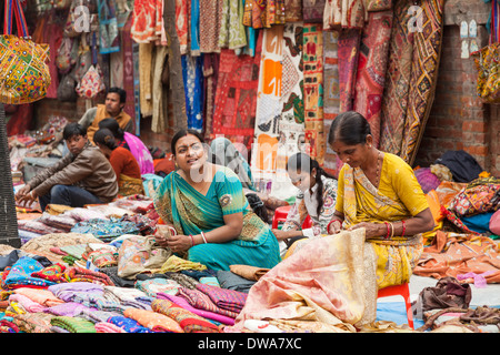 Indische Frauen in bunten traditionellen Saris, bunte Stoffen in einem lokalen Markt am Straßenrand verkaufen gekleidet Stockfoto