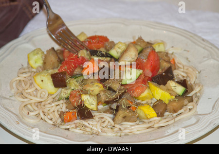 Nahaufnahme von Gabel und einem Teller voller mediterraner Pasta mit Gemüse Stockfoto