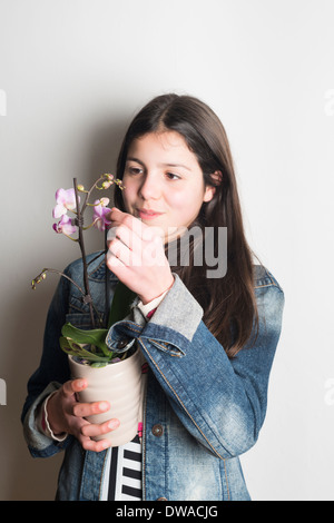 Teenager-Mädchen bewundert Orchidee Pflanze Stockfoto