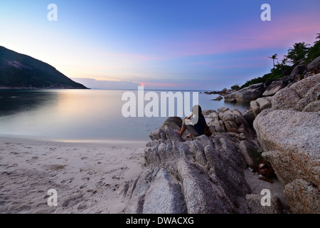 Touristen am Strand sitzen und beobachten einen atemberaubenden Sonnenuntergang am Haad Khuad, Koh Phangan, Süd-Thailand. Bewegungsunschärfe auf Stockfoto