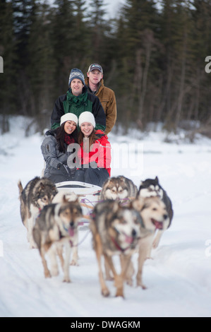 Foto von vier Personen Reiten im Schlittenhunderennen in Alaska Stockfoto