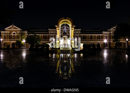Saranrom Palast (Thai Ministerium für auswärtige Angelegenheiten) in der Nacht mit einer Statue des Königs wider auf den Fliesen. Stockfoto