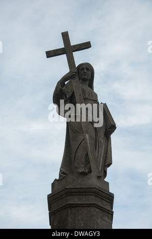 Statue von Frau hält ein Kreuz und eine Bibel. Es ist die Spitze einer Lagerstätte in Prazeres Cemetery in Campo de Ourique, Lissabon. Stockfoto