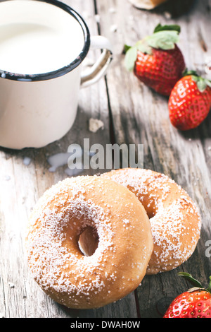 Zucker Donuts und frischen Erdbeeren und Vintage Becher Milch auf Holztisch serviert. Stockfoto