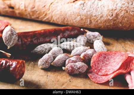 Satz von Salami serviert mit frischem Brot auf alten Holzbrett. Stockfoto