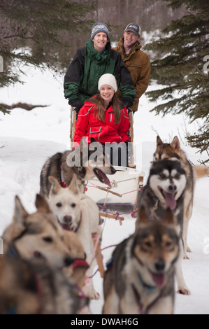 Foto von drei Personen Reiten im Schlittenhunderennen in Alaska Stockfoto