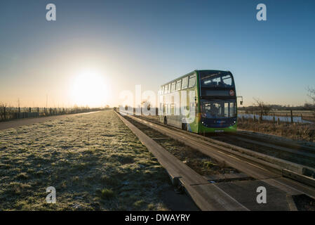 Longstanton, Cambridgeshire, Großbritannien. 5. März 2014. Ein geführte Bus fährt bei Sonnenaufgang auf die geführte Busway in Richtung Cambridge UK an einem frostigen und sonnigen Morgen 5. März 2014.  Ein sonniger Tag im Osten Englands heute mit ein wenig wärmer Prognose später in der Woche erwartet.  Die geführte Busway verläuft von Cambridge nach St. Ives in Cambridgeshire und ist die längste in der Welt mit Busse auf einem speziell dafür gebauten konkrete verfolgen.  Kredit Julian Eales/Alamy Live-Nachrichten Stockfoto