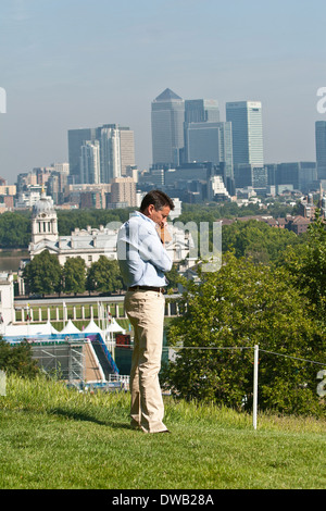 Lord Coe am Telefon durch das Royal Observatory in Greenwich mit Canary Wharf im Hintergrund Stockfoto