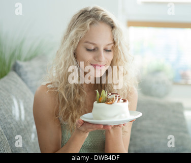 Schöne junge Frau, die verlockenden Kuchen im Haus zu betrachten Stockfoto
