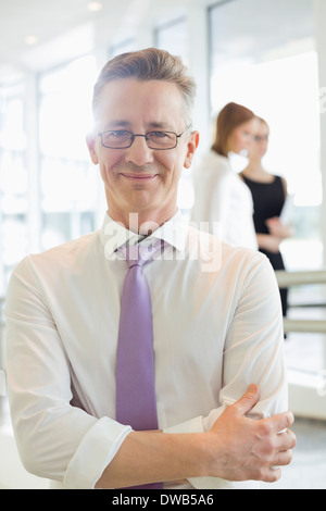 Porträt von zuversichtlich Geschäftsmann stehend Arme gekreuzt im Büro Stockfoto