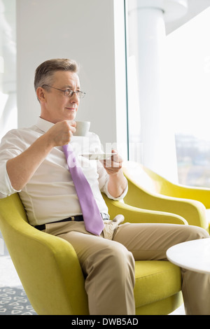 Reife Geschäftsmann mit Kaffee in der Lobby im Büro Stockfoto