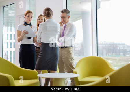 Business-Leute diskutieren über Dokumente in lobby Stockfoto