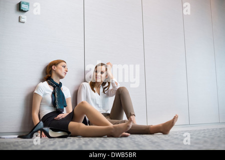 Müde Geschäftsfrauen auf Boden im Büro sitzen Stockfoto