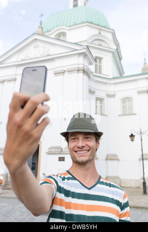 Junger Mann unter Selbstporträt außerhalb St. Kasimir Kirche, Warschau, Polen Stockfoto