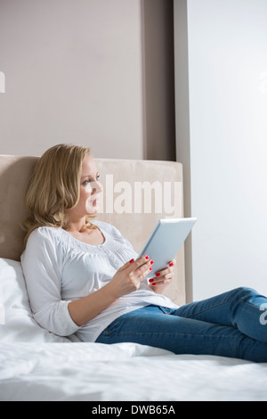 Nachdenklich Mitte Erwachsene Frau mit digital-Tablette im Schlafzimmer Stockfoto