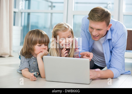 Glücklicher Vater zeigen etwas für Kinder am Laptop zu Hause Stockfoto