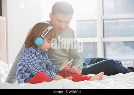 Vater mit junge Musik hören über Kopfhörer im Schlafzimmer Stockfoto