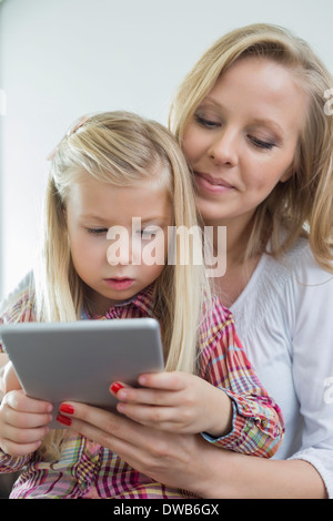 Liebende Frau mit Tochter, die mit digital-Tablette zu Hause Stockfoto