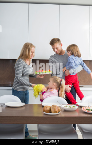 Glückliche Familie mit Kindern, die mit Essen in der Küche Stockfoto