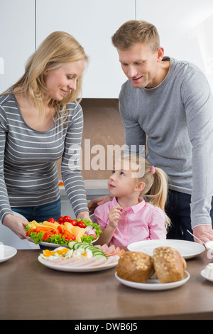 Glückliche Eltern mit Tochter mit Mahlzeit in Küche Stockfoto