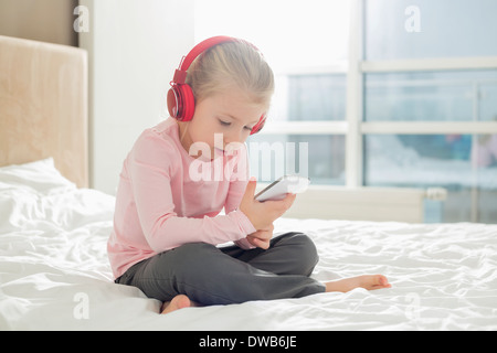 Gesamte Länge der Mädchen hören von Musik über Kopfhörer im Schlafzimmer Stockfoto