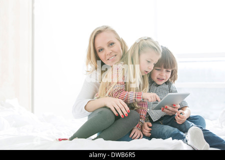 Porträt der glückliche Mutter mit Kindern bei der Nutzung digitalen Tablets im Schlafzimmer Stockfoto