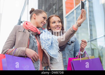 Freundinnen mit Einkaufstüten unter Selbstportrait durch Handy Stockfoto