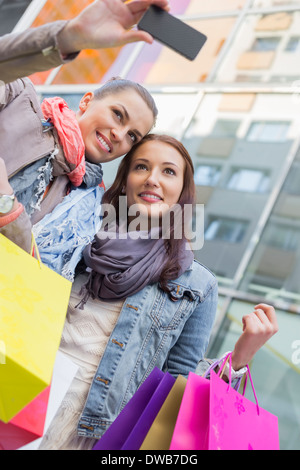 Frauen mit Einkaufstaschen unter Selbstportrait durch Handy Stockfoto