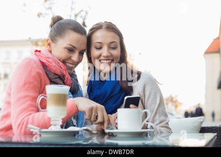 Glücklich Freundinnen mit Handy im Straßencafé Stockfoto