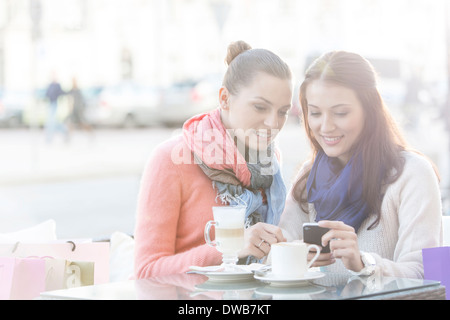 Glückliche Frauen mit Handy im Straßencafé im winter Stockfoto