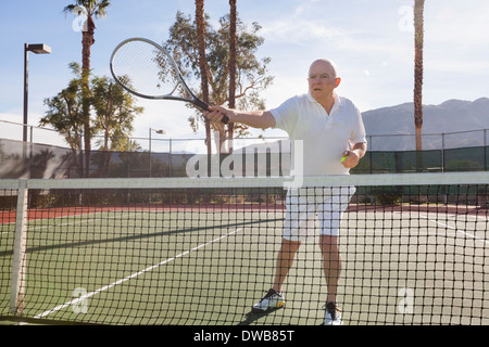 Senior Tennisspieler auf Gericht servieren wird vorbereitet Stockfoto