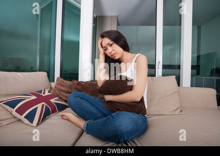 Voller Länge besorgt junge Frau sitzt auf dem sofa Stockfoto