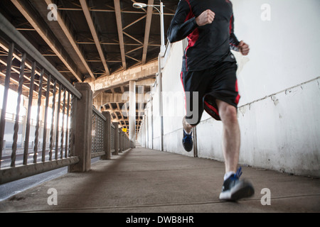 Schuss der junge Mann läuft auf Stadtbrücke beschnitten Stockfoto