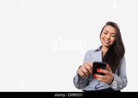 Glücklich Geschäftsfrau Textnachrichten durch Smartphone vor grauem Hintergrund Stockfoto