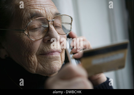 Ältere Frau am Telefon mit Kreditkarte Stockfoto