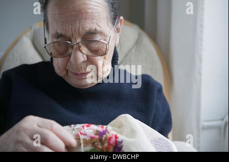 Ältere Frau tun Kreuzstich Stockfoto