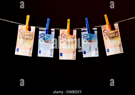 Euro-Banknoten hängt an einer Wäscheleine Agianst einen schwarzen Hintergrund. Stockfoto