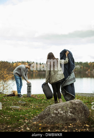 Junges Paar mit Decke und Schlafsack am Seeufer Stockfoto