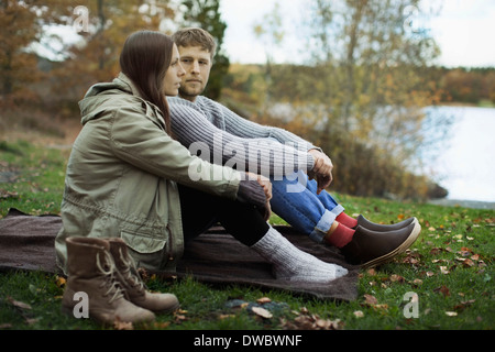 Junges Paar in Winterkleidung auf Decke sitzend und camping Stockfoto