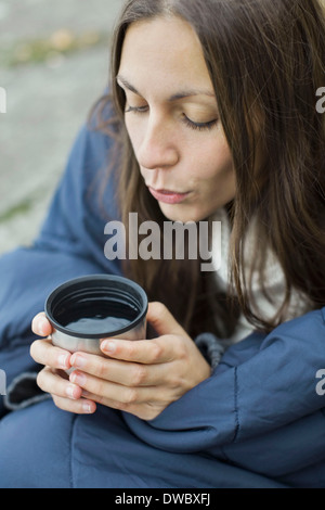 Frau in Decke weht auf Kaffee gewickelt Stockfoto